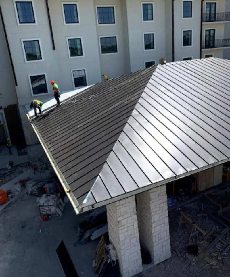 Crew installing standing seam metal roof panels on a commercial project in Villa Hills
